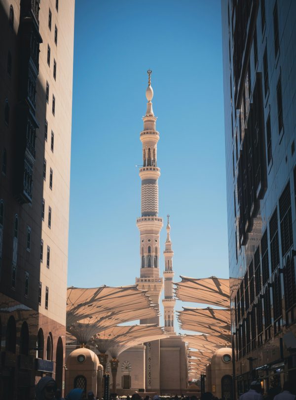 The Prophet's Mosque and its iconic minarets viewed between two buildings in Medina, Saudi Arabia.